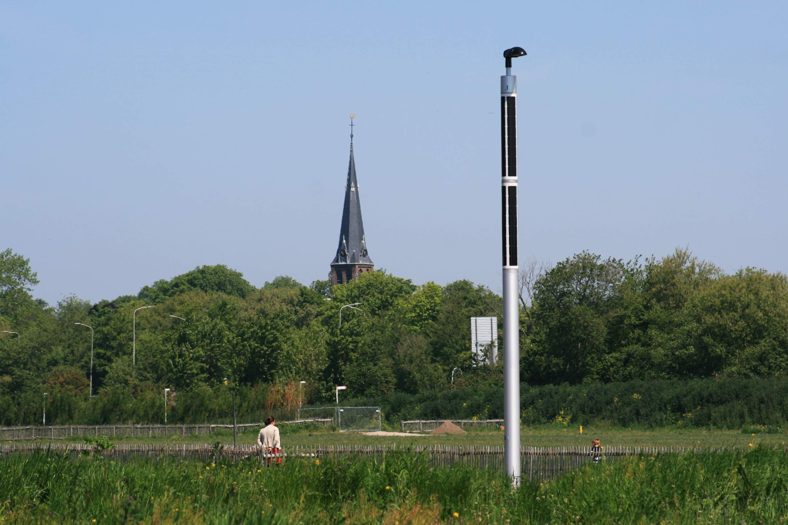 Milieuvriendelijke Soluxio solarstraatverlichting in Nederland Milieuvriendelijke Soluxio solarstraatverlichting in een veld in Nederland, met op de achtergrond een kerktoren die boven de boomgrens uitsteekt